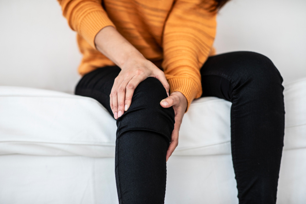 woman-knee-pain-on-sofa